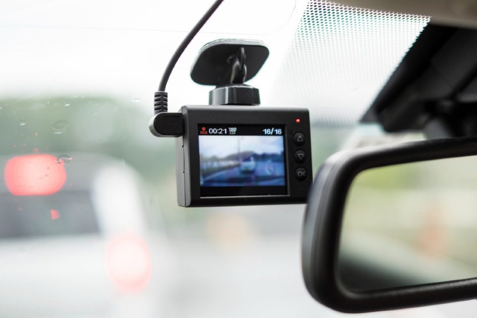 A dash camera recording the front view of a car with rain drops visible on the windshield.