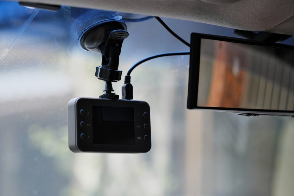 A car camera recorder is mounted on the front windshield, positioned to capture a clear view of the road ahead.