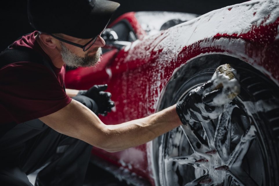 ed Sportscar's Wheels Covered in Shampoo Being Rubbed by a Soft Sponge at a Stylish Dealership Car Wash